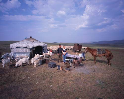 Chinese families in front of their homes with their household possessions.