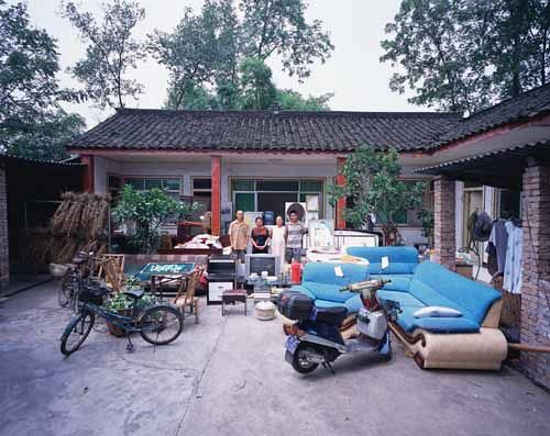 Chinese families in front of their homes with their household possessions.