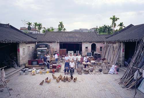 Chinese families in front of their homes with their household possessions.