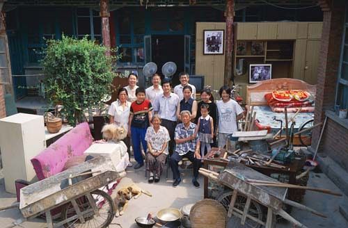 Chinese families in front of their homes with their household possessions.