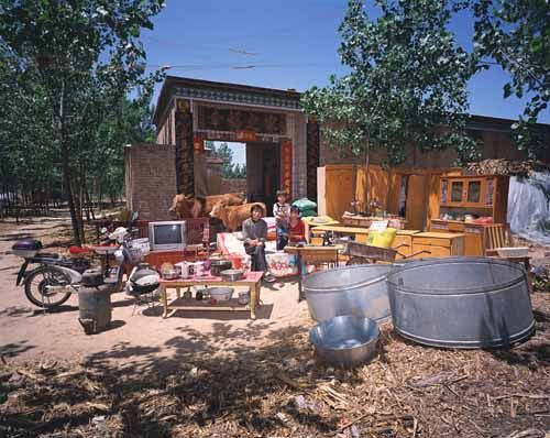 Chinese families in front of their homes with their household possessions.