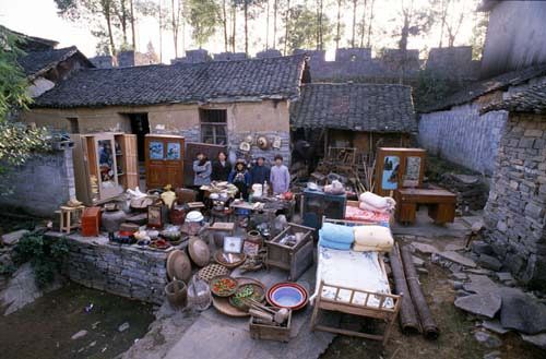 Chinese families in front of their homes with their household possessions.